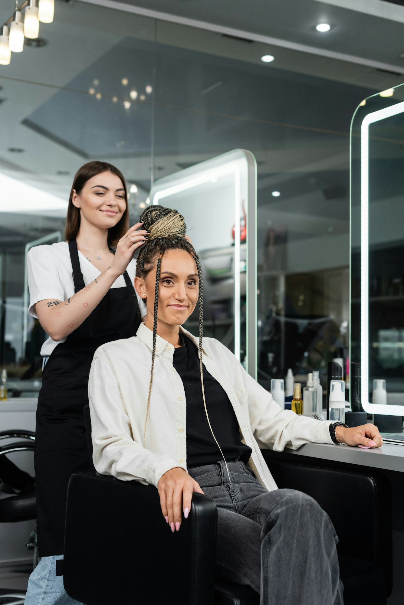 hair make over,cheerful hair stylist doing hair bun to female client with braids,cheerful women