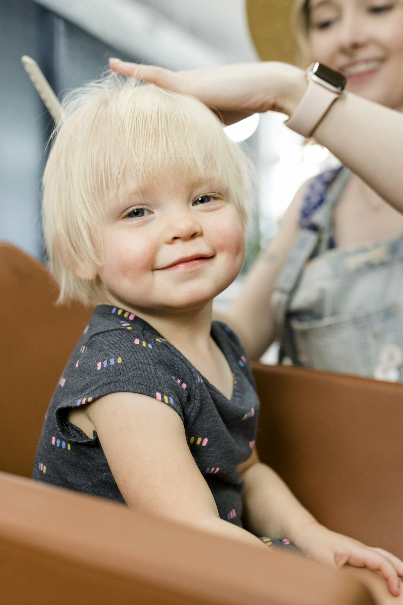 Hairstylist giving a haircut to an adorable blond kid