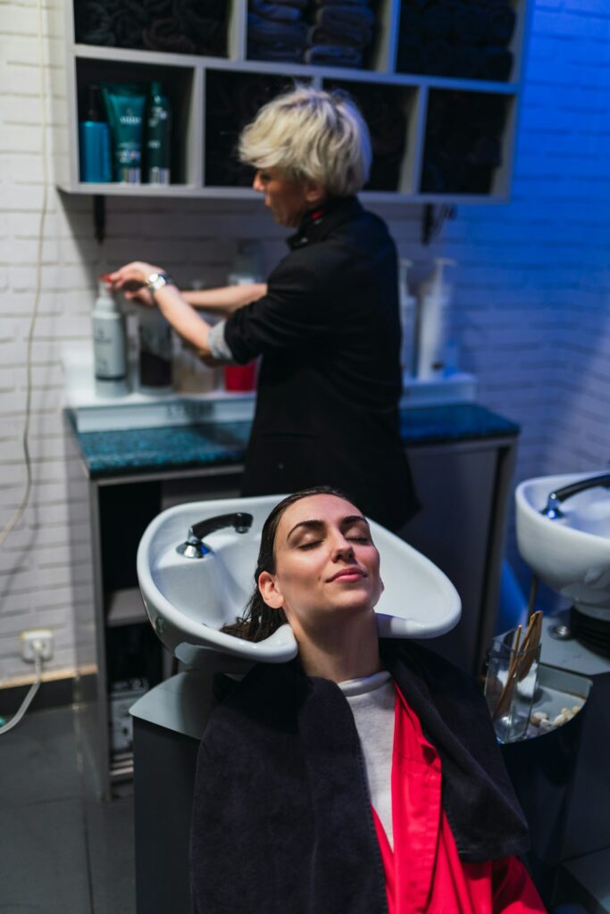 Woman washing hairs of young lady